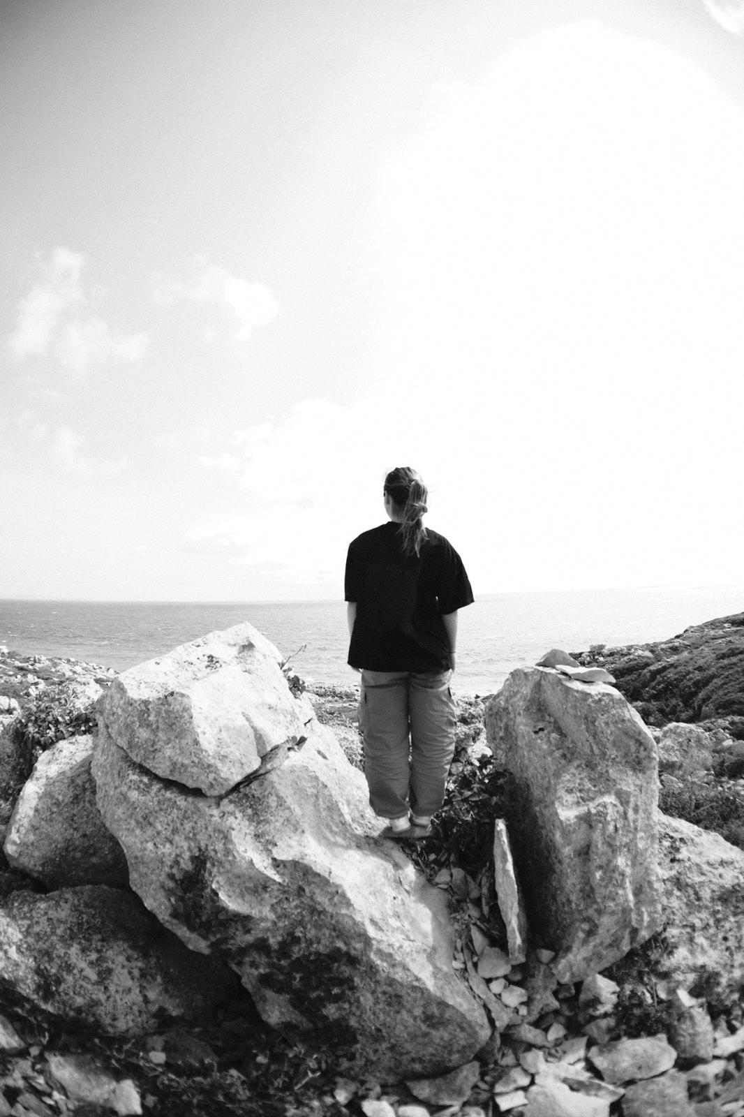 Person standing on large rocks by the ocean